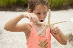 A child holds a starfish on a Sanibel Island beach