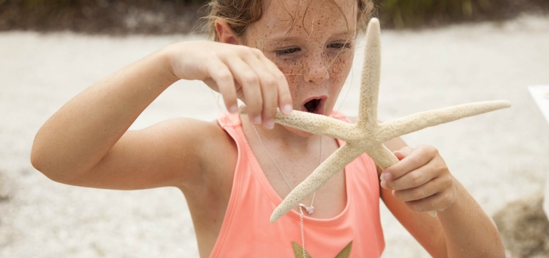 A child holds a starfish on a Sanibel Island beach