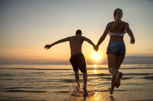 Couple running into water at sunrise
